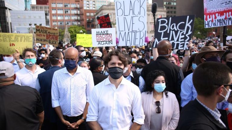 Canadian President Justin Trudeau kneels down alongside protesters